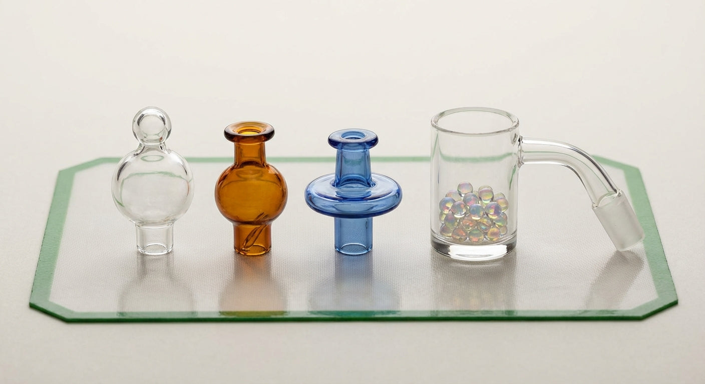 Close-up photo of three carb caps (bubble, directional, spinner) sitting next to a quartz bucket banger and terp pearls