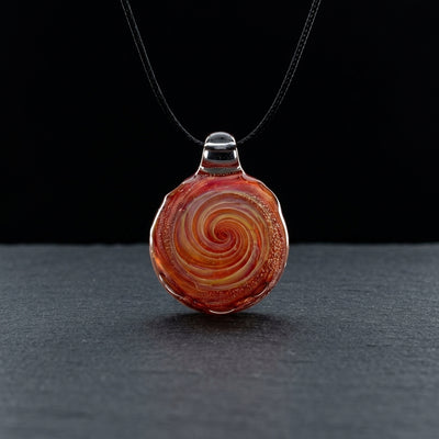 2" Red Spiral Pendant on dark slate surface - Oil Slick Pad