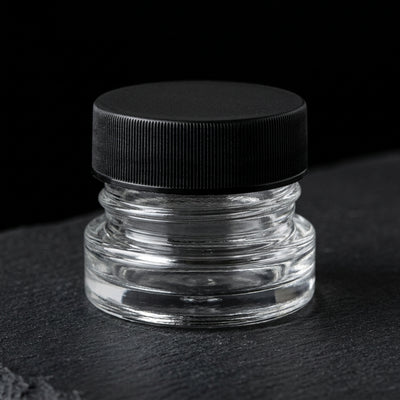 9ml child resistant glass jar with ribbed black lid on slate