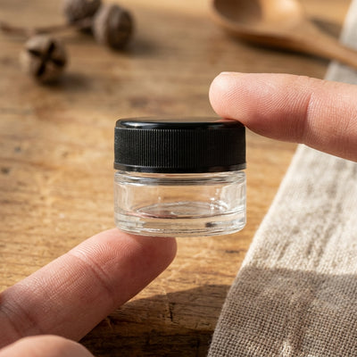 9ml child resistant jar held between fingers for scale