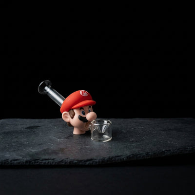 Red Plumber Glass Hand Pipe on dark slate surface - Oil Slick Pad